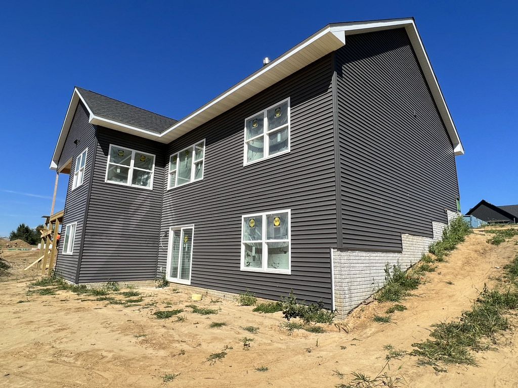 A large house is sitting on top of a dirt hill.