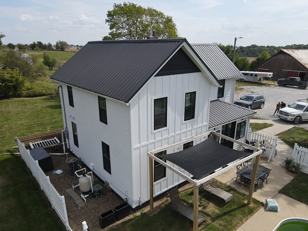 An aerial view of a white house with a black roof