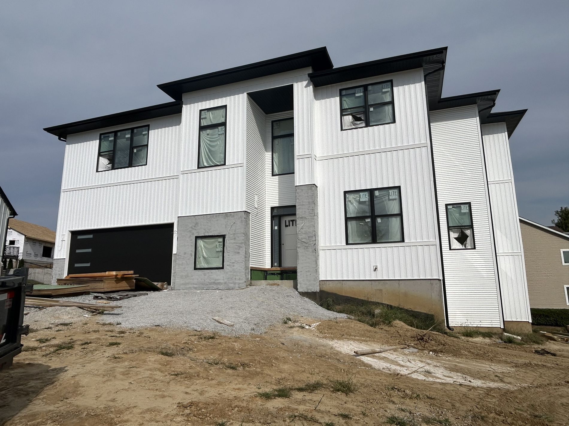 A large white house with black trim is being built.
