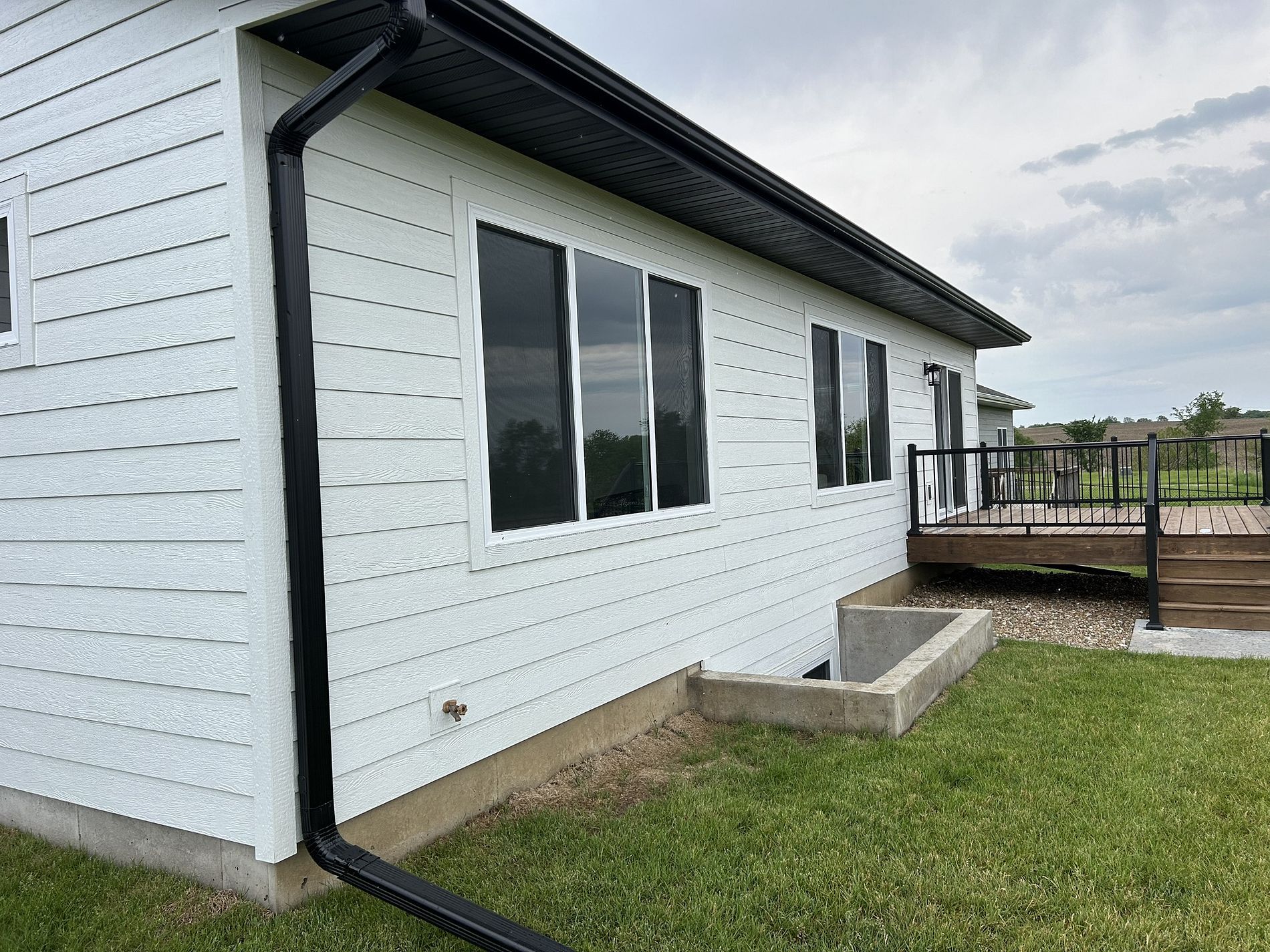 A white house with a black gutter and a deck.