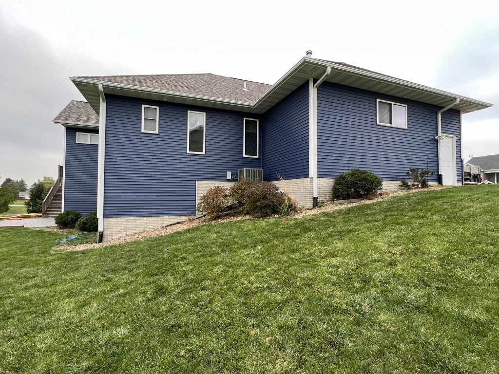 A blue house is sitting on top of a lush green hill.