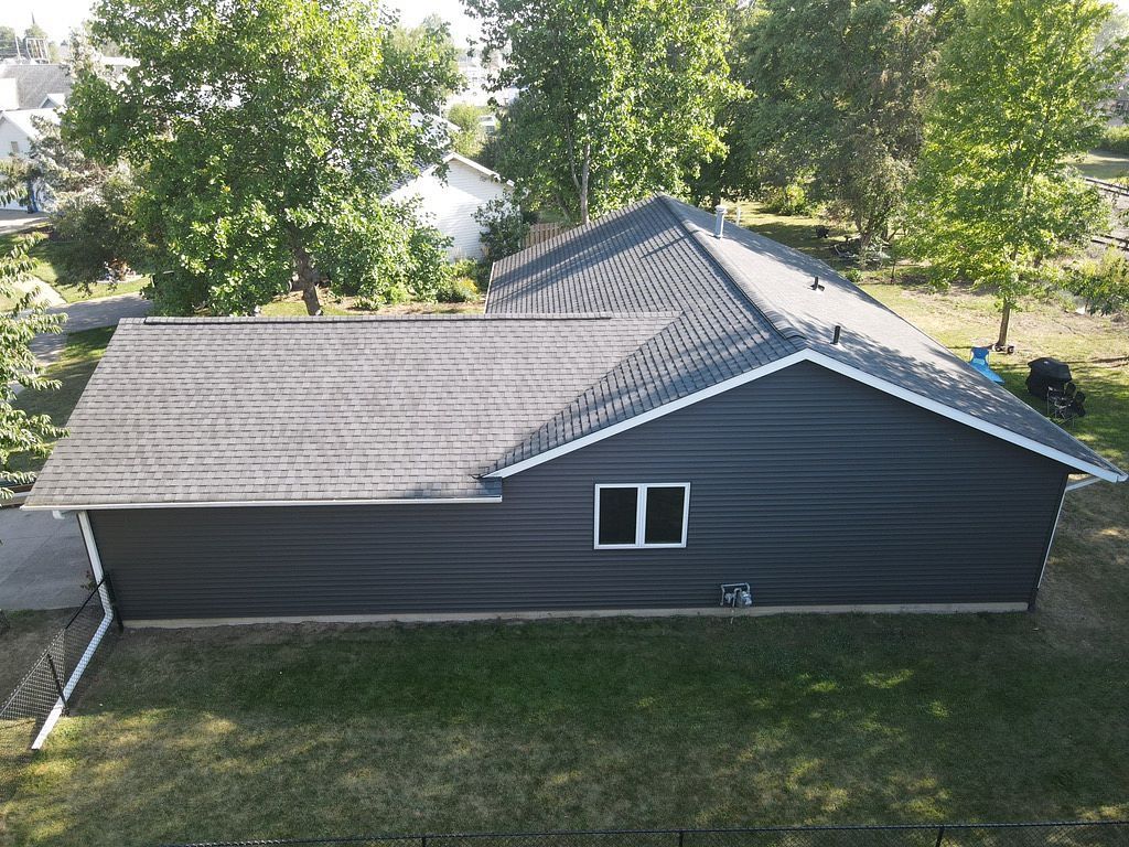 An aerial view of a house with a roof that is surrounded by trees.