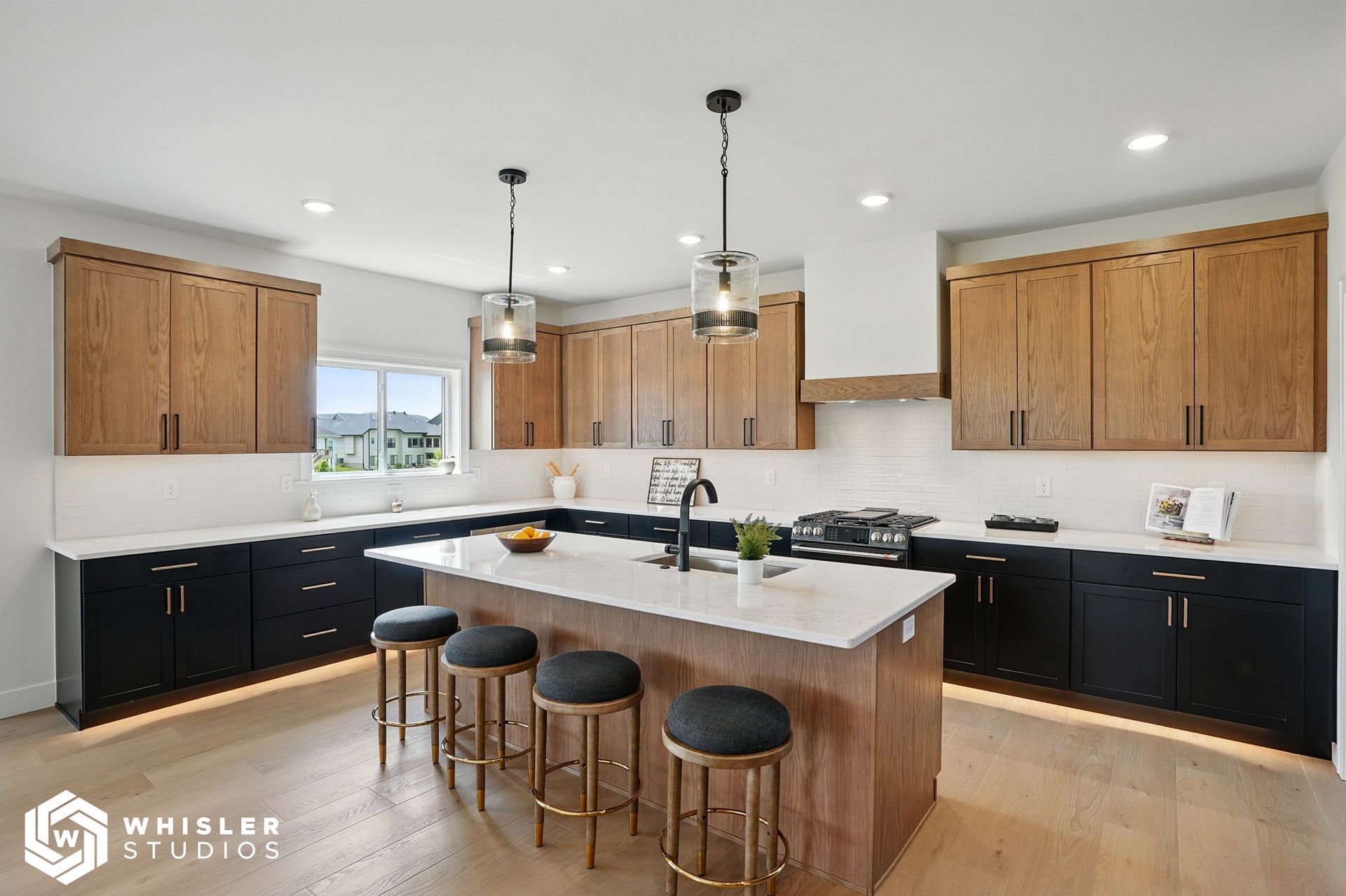 A kitchen with black cabinets, white counter tops, and a large island.