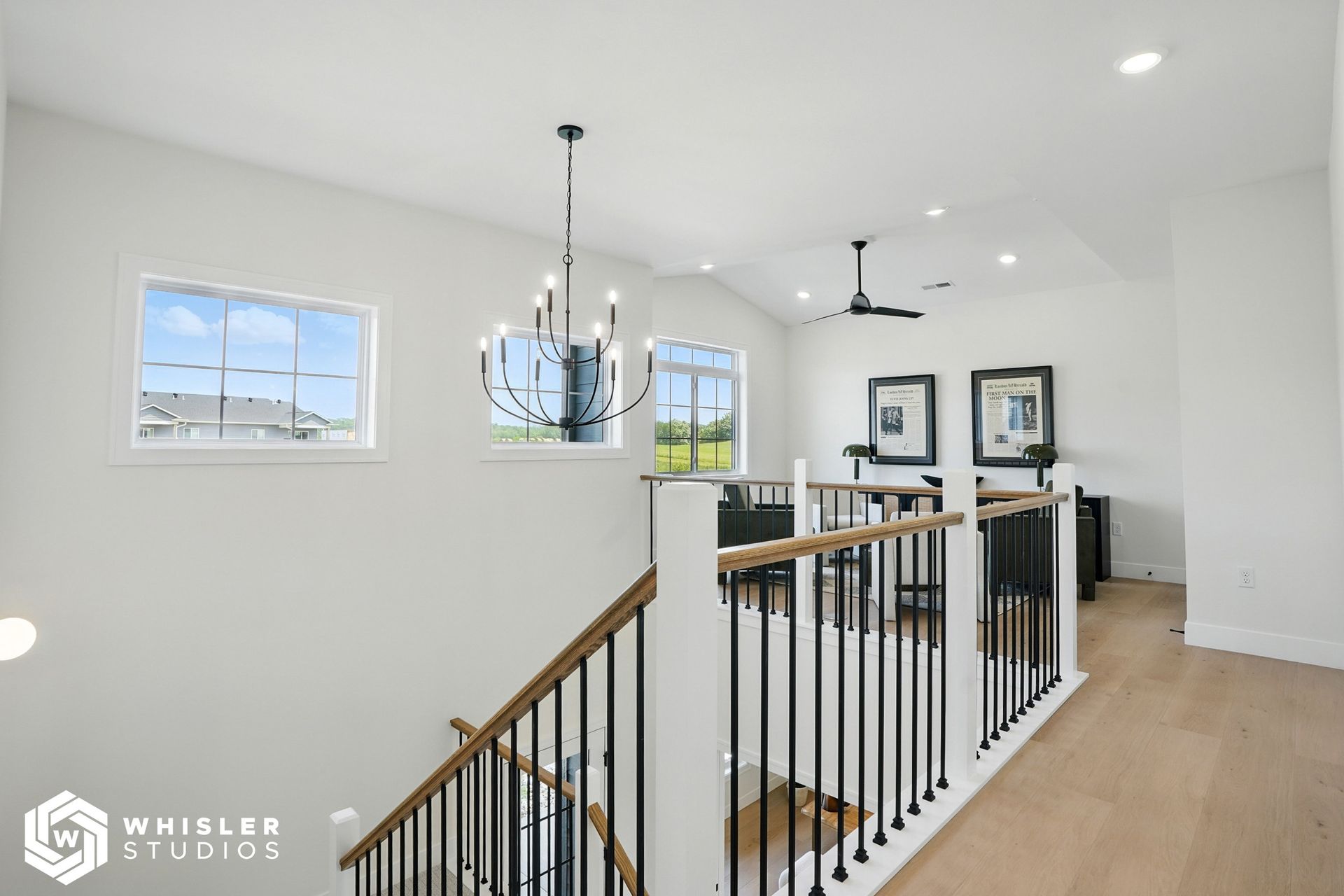 A staircase in a house with a ceiling fan and a chandelier hanging from the ceiling.