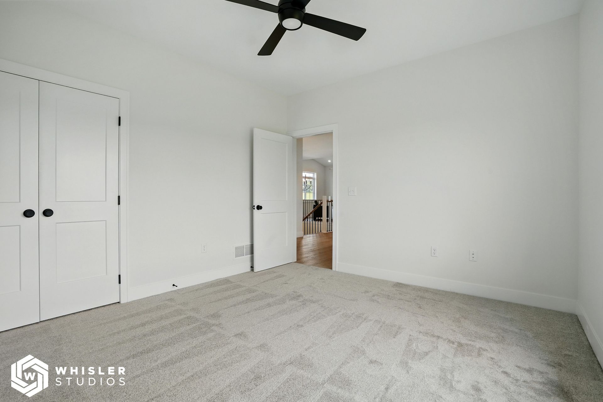 A bedroom with white walls and a ceiling fan