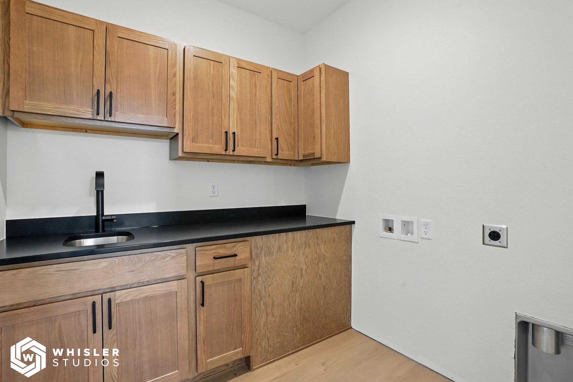 A kitchen with wooden cabinets, black counter tops, and a sink.