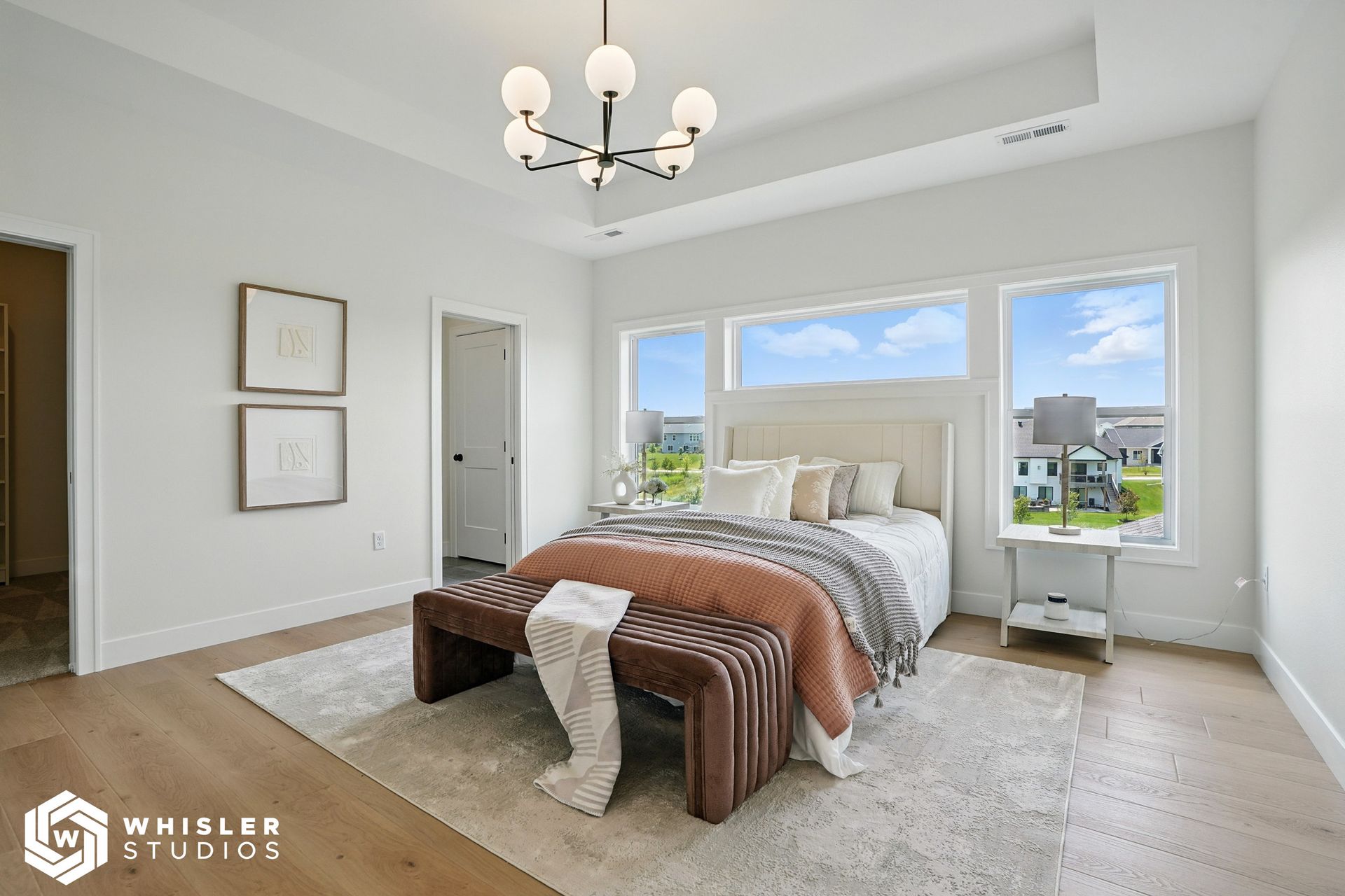 A bedroom with a bed, bench, and windows.