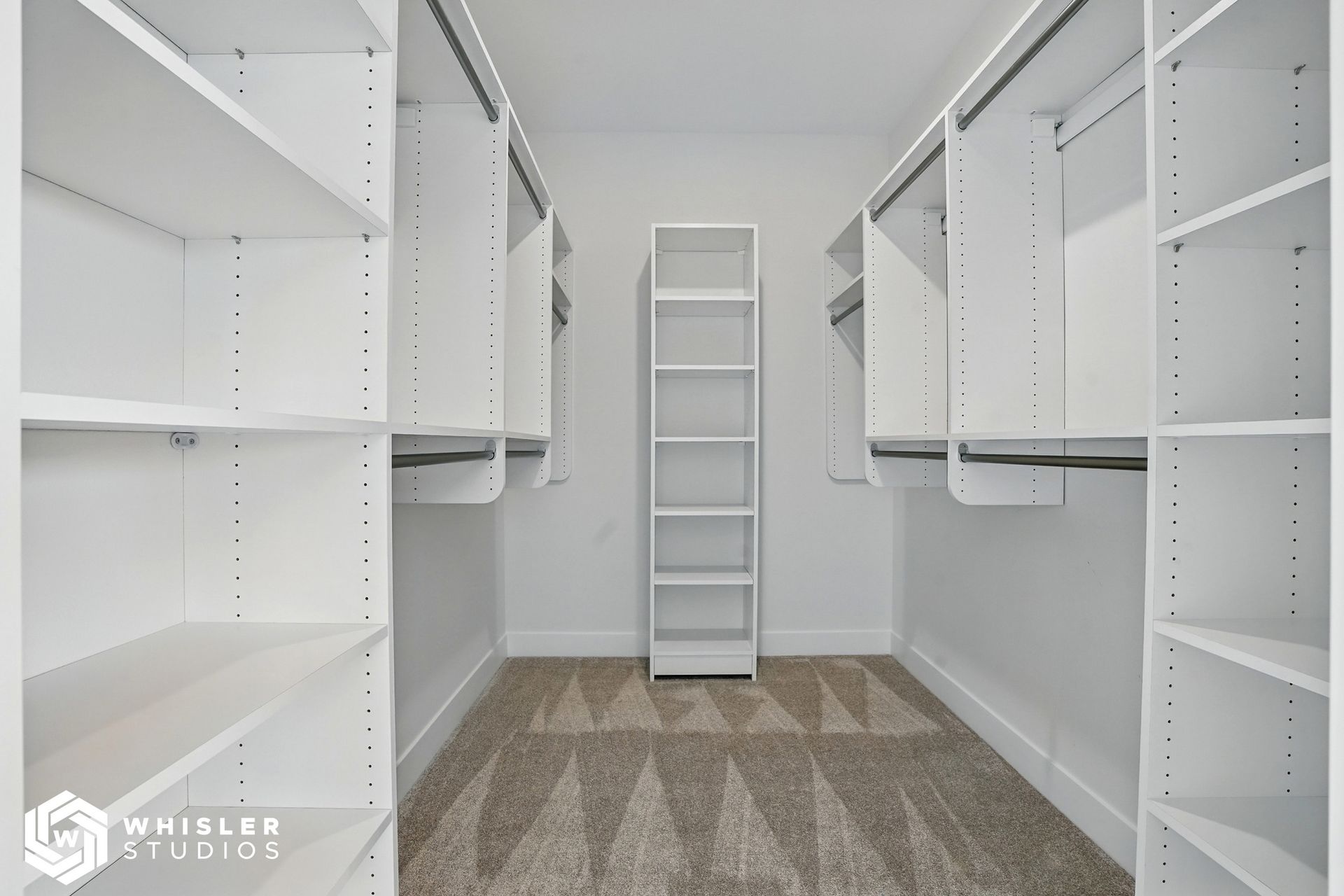 A walk in closet with lots of shelves and a shelf in the middle.