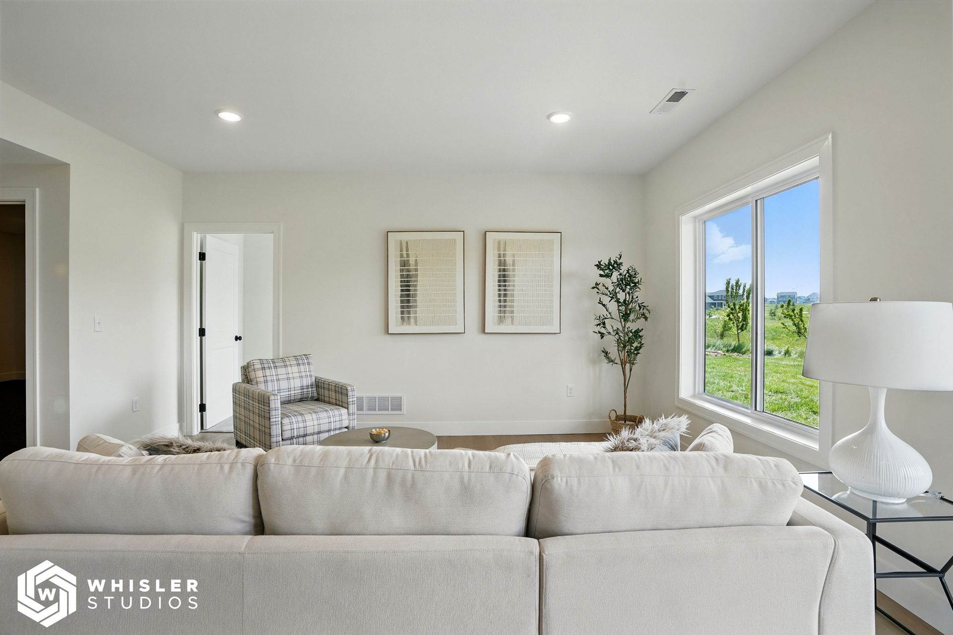 A living room with a couch, chair, lamp, and window.