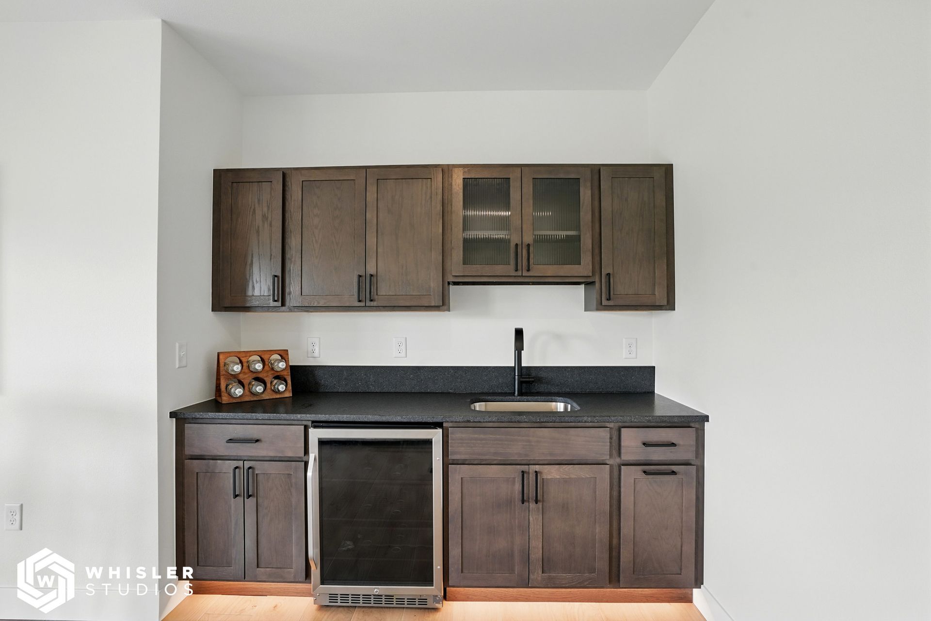 A kitchen with wooden cabinets, a sink, and a refrigerator.
