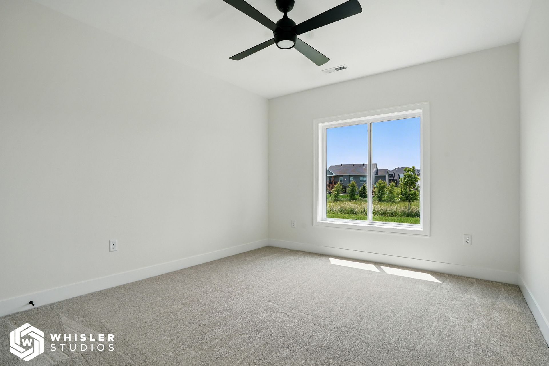 An empty bedroom with a ceiling fan and a window.