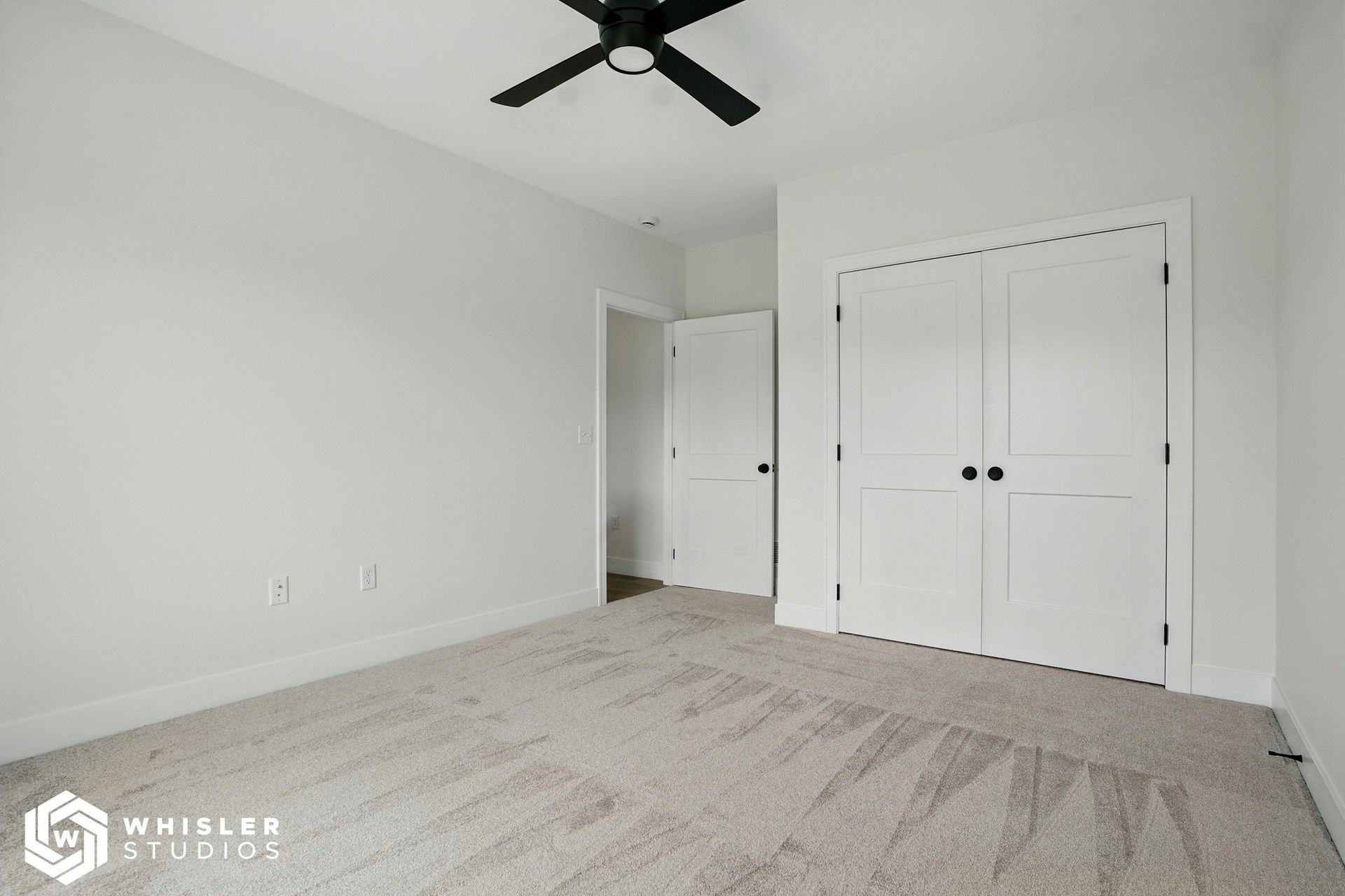An empty bedroom with a ceiling fan and closets