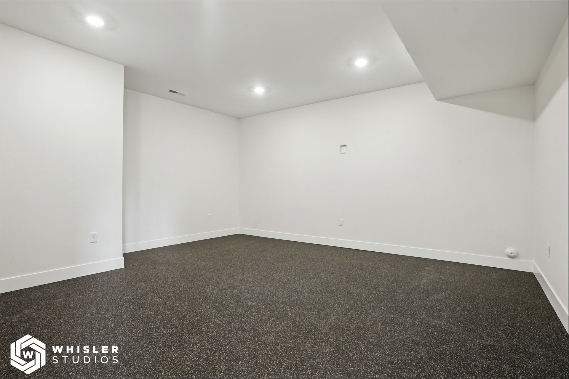 An empty basement with a carpeted floor and white walls.
