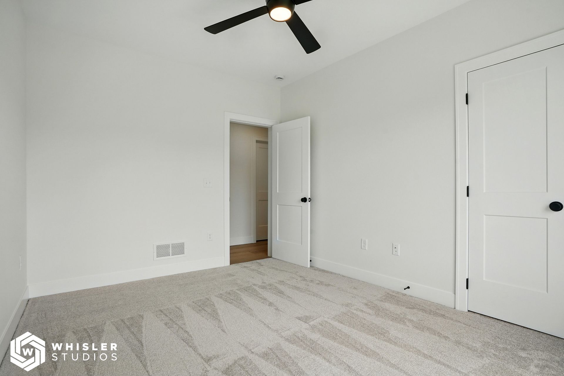 An empty bedroom with a ceiling fan and a door.