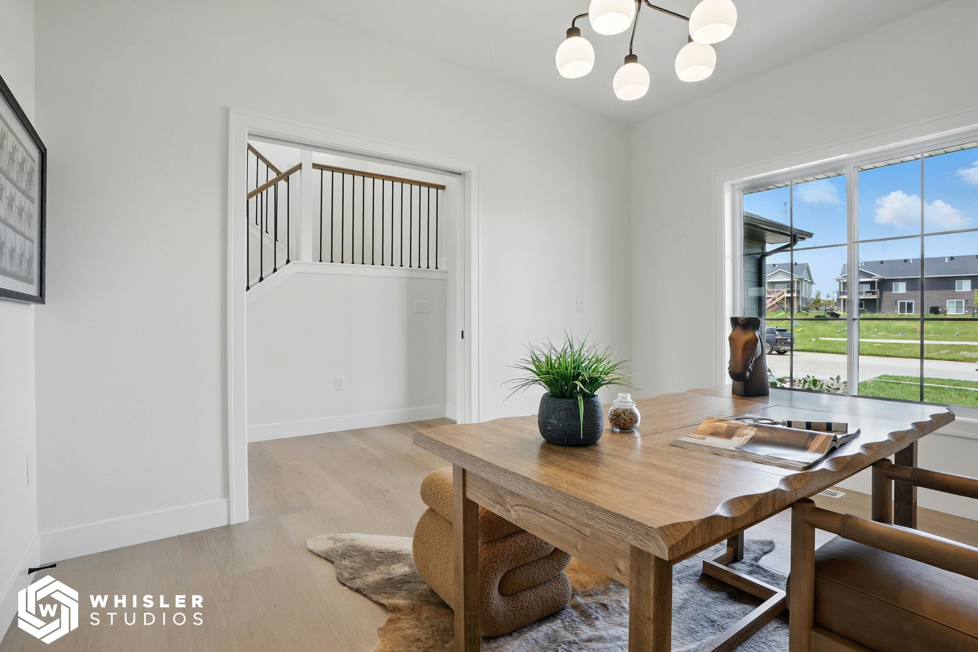 A living room with a wooden table and chairs and a large window.