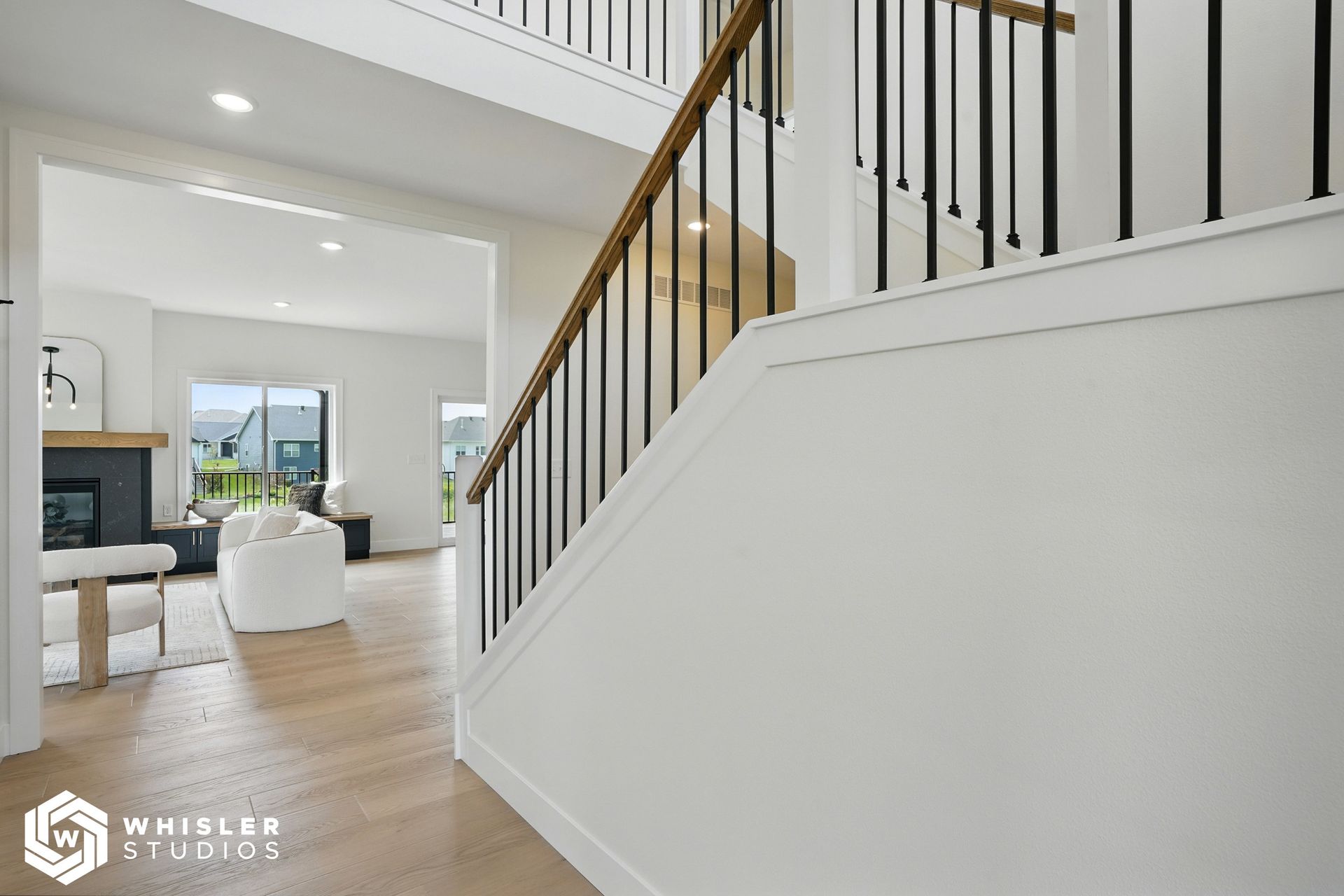 A white staircase with a black railing leading up to a living room.