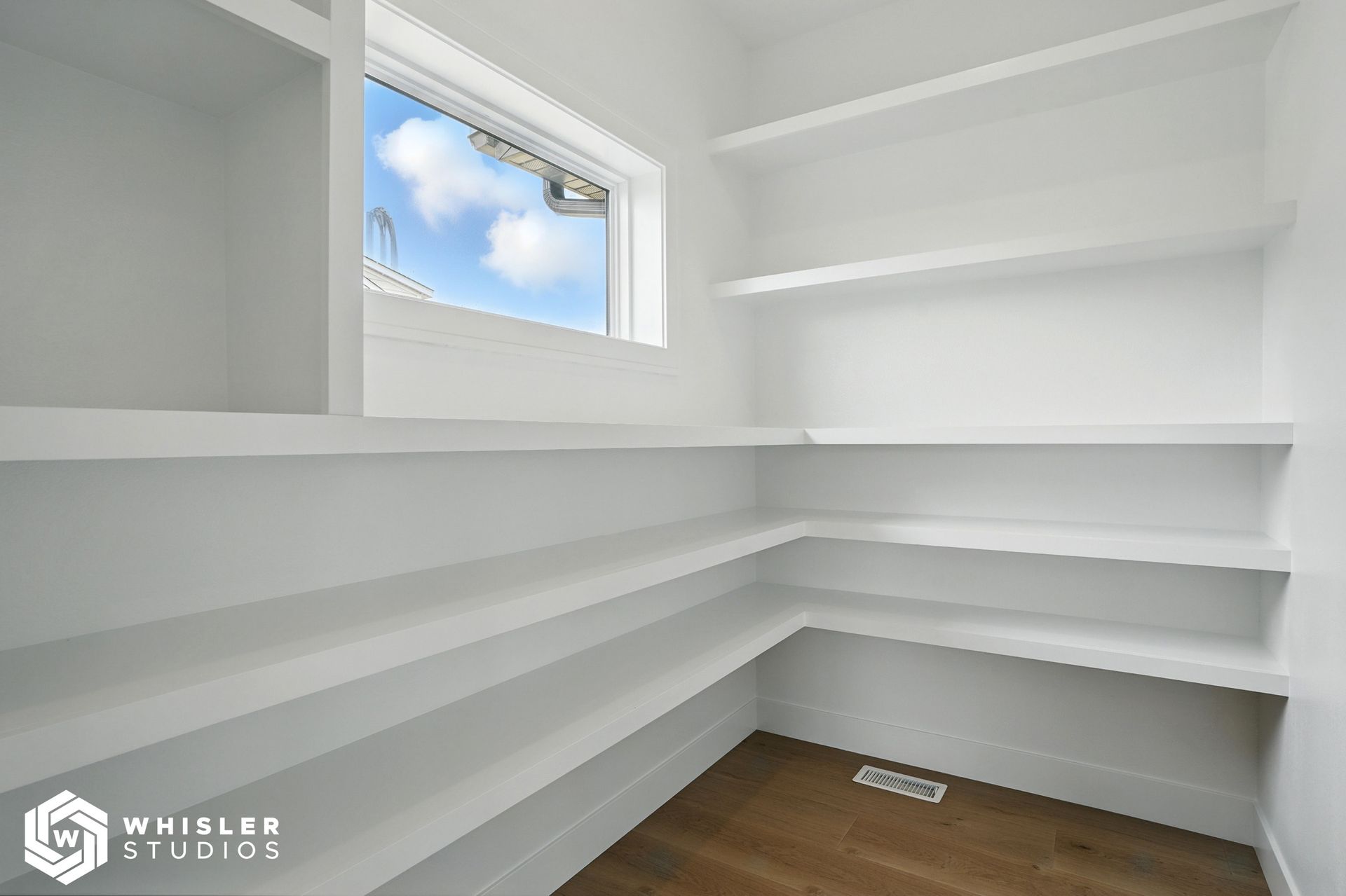 An empty room with white shelves and a window.