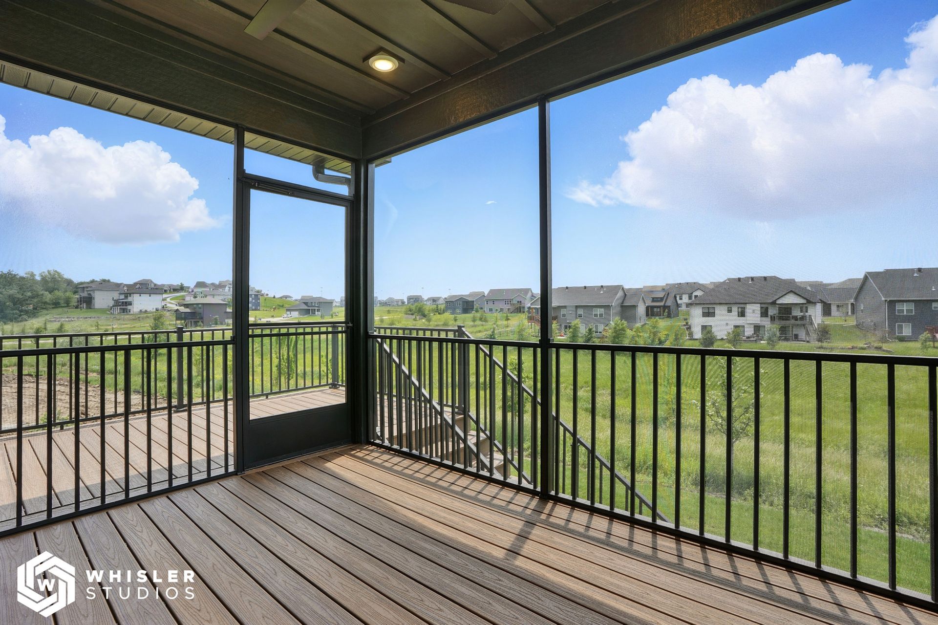A screened in porch with a view of a field and houses.