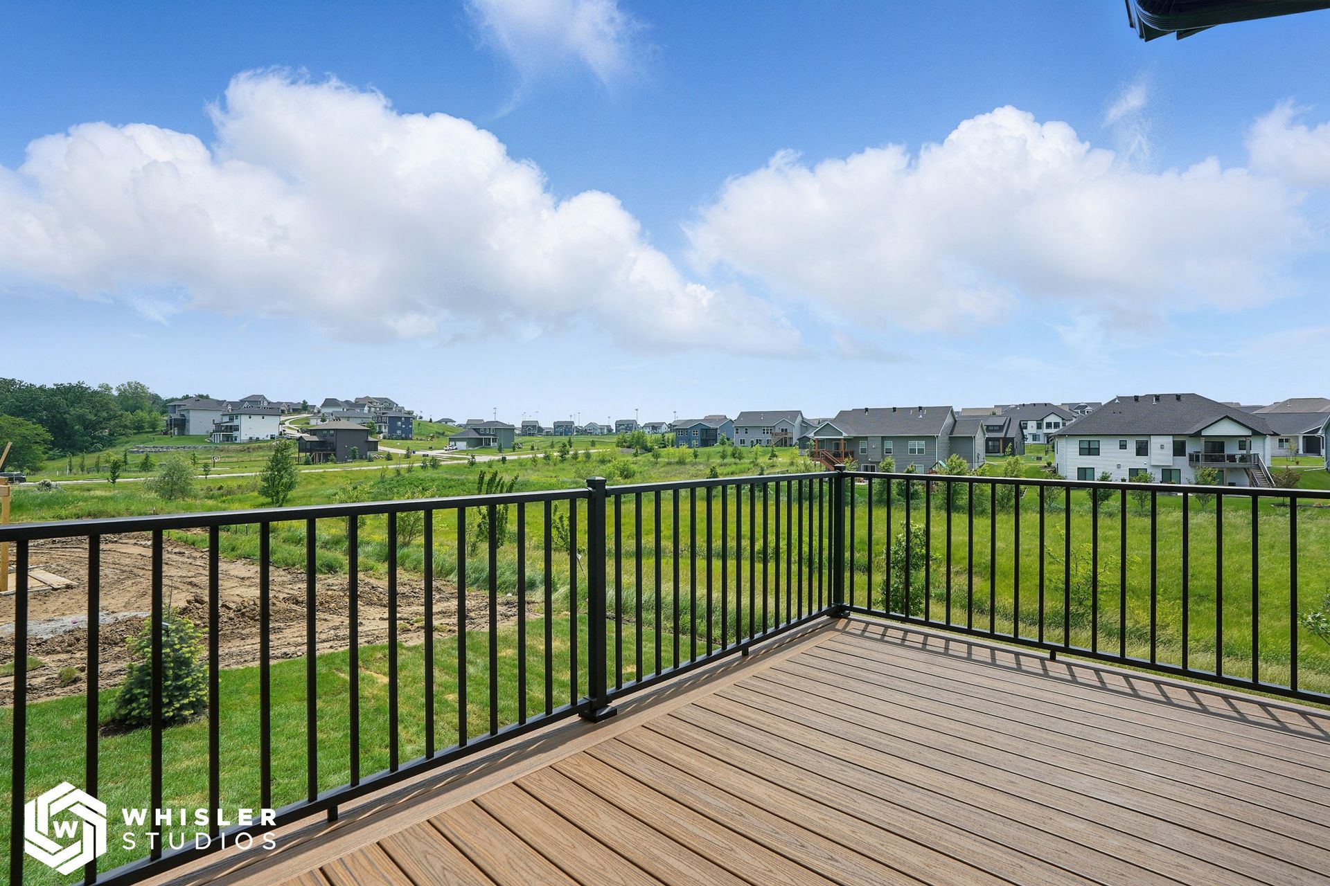 A balcony with a view of a field and houses