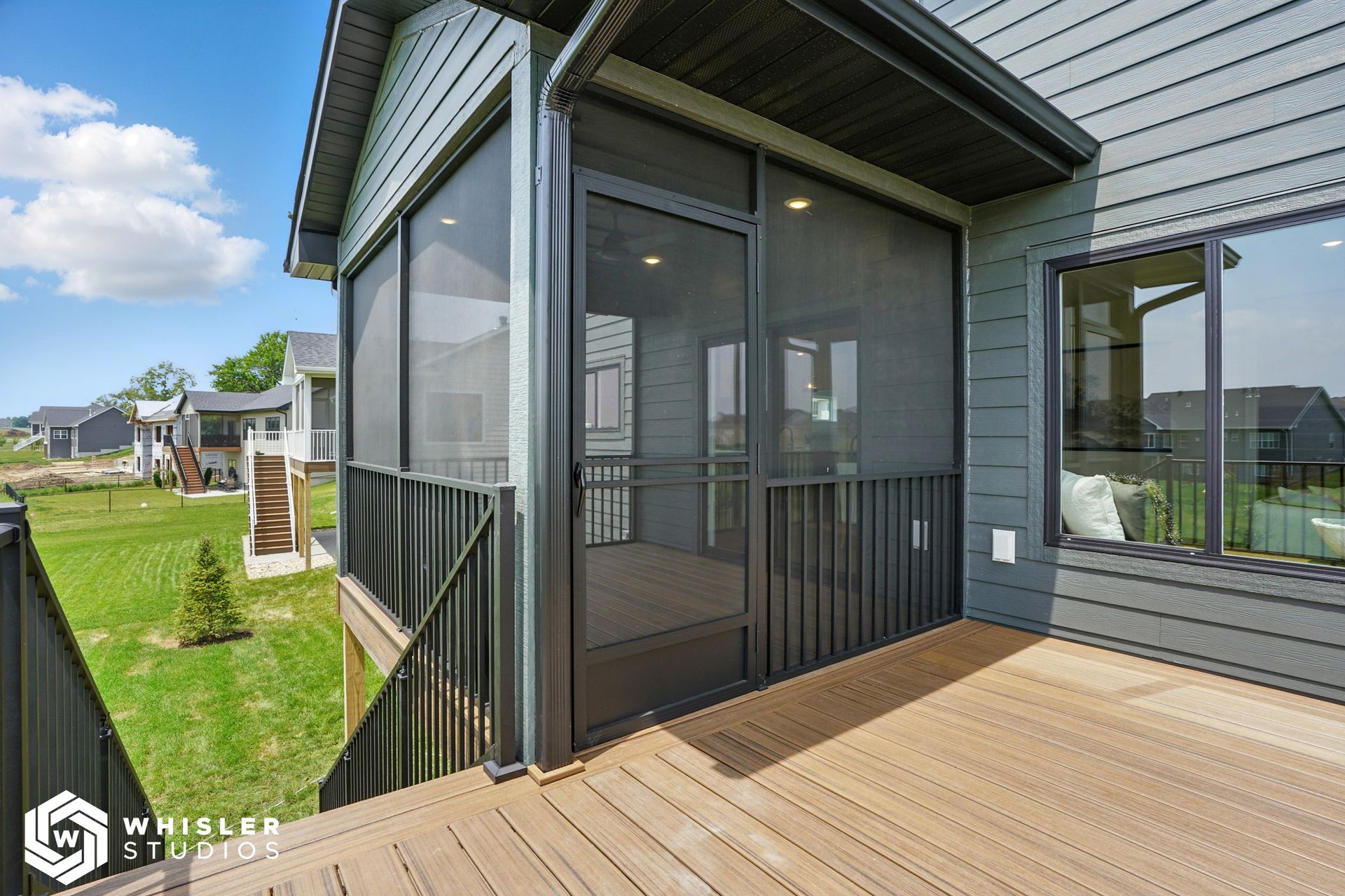 A screened in porch with a wooden deck next to a house.