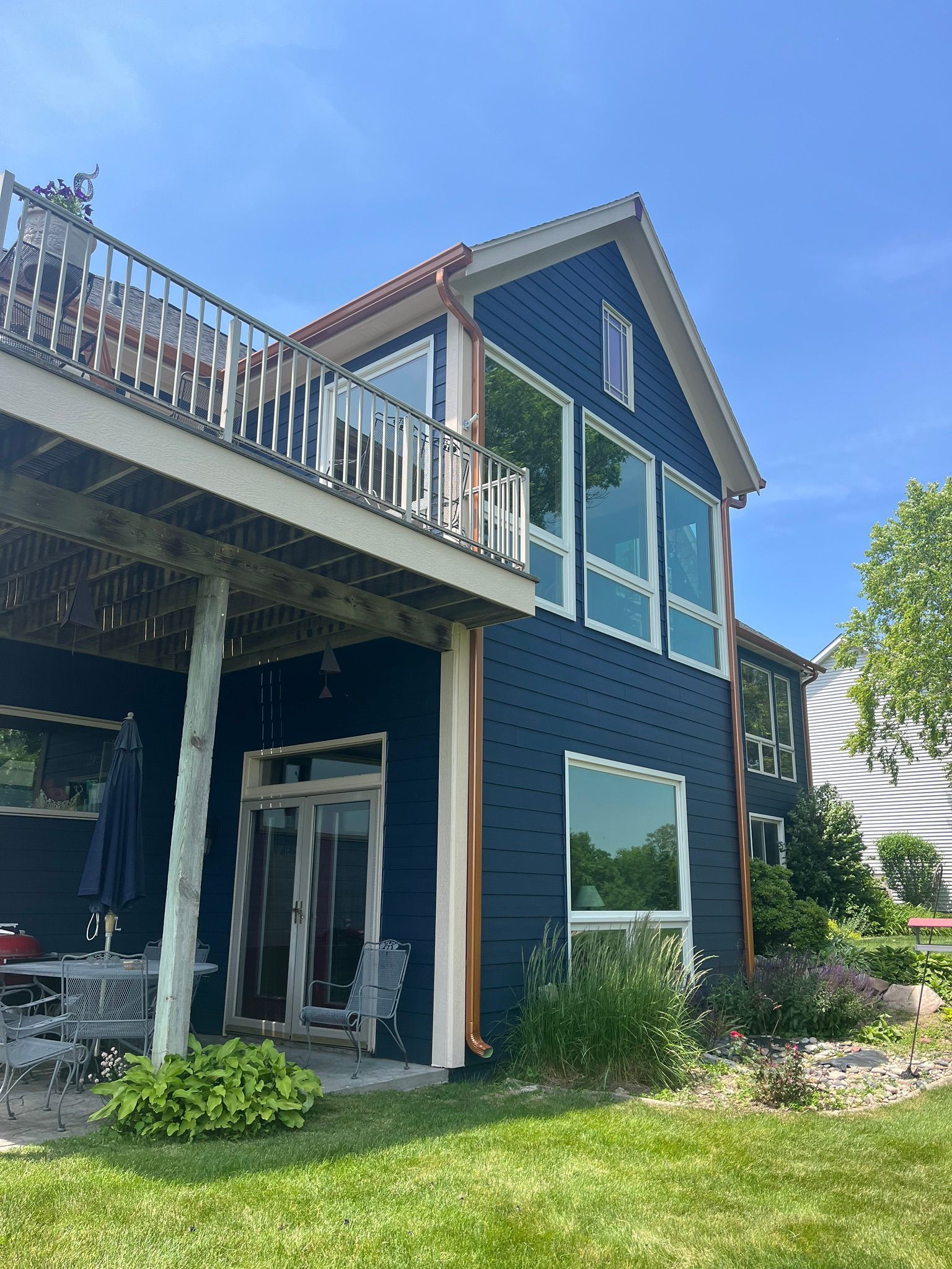 A large blue house with a deck and a lot of windows