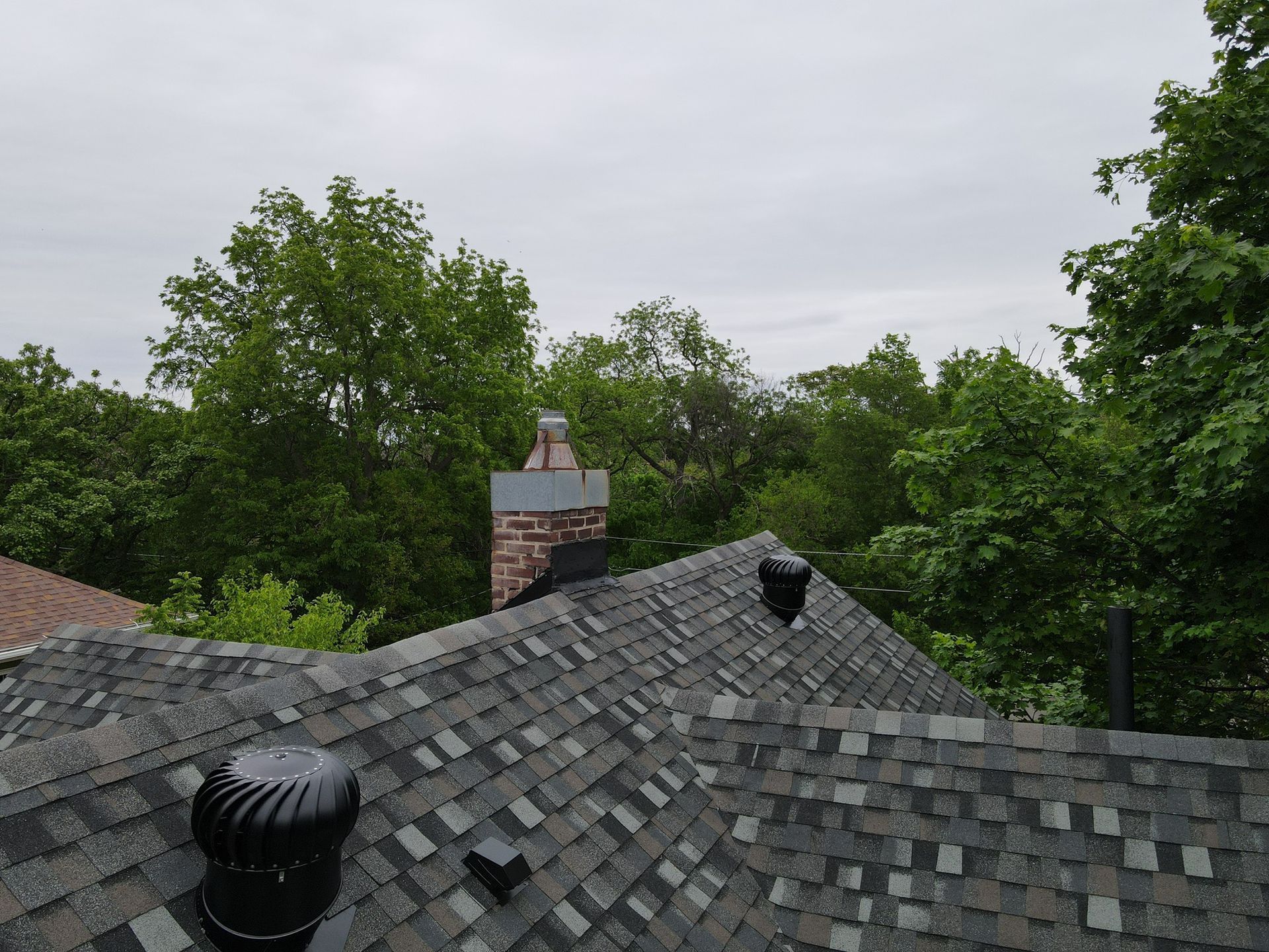 A roof with a chimney on it and trees in the background