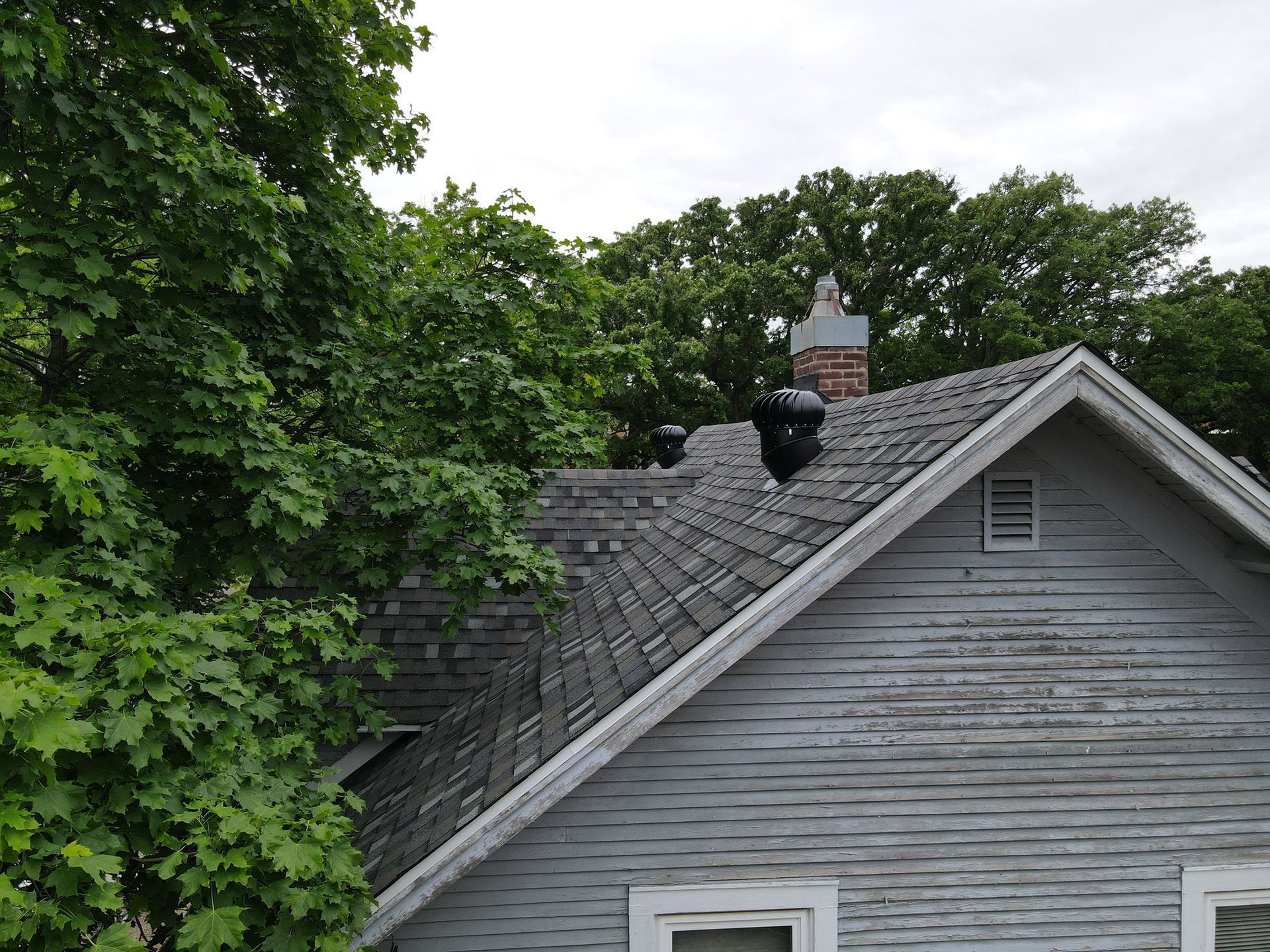 A house with a chimney on the roof is surrounded by trees