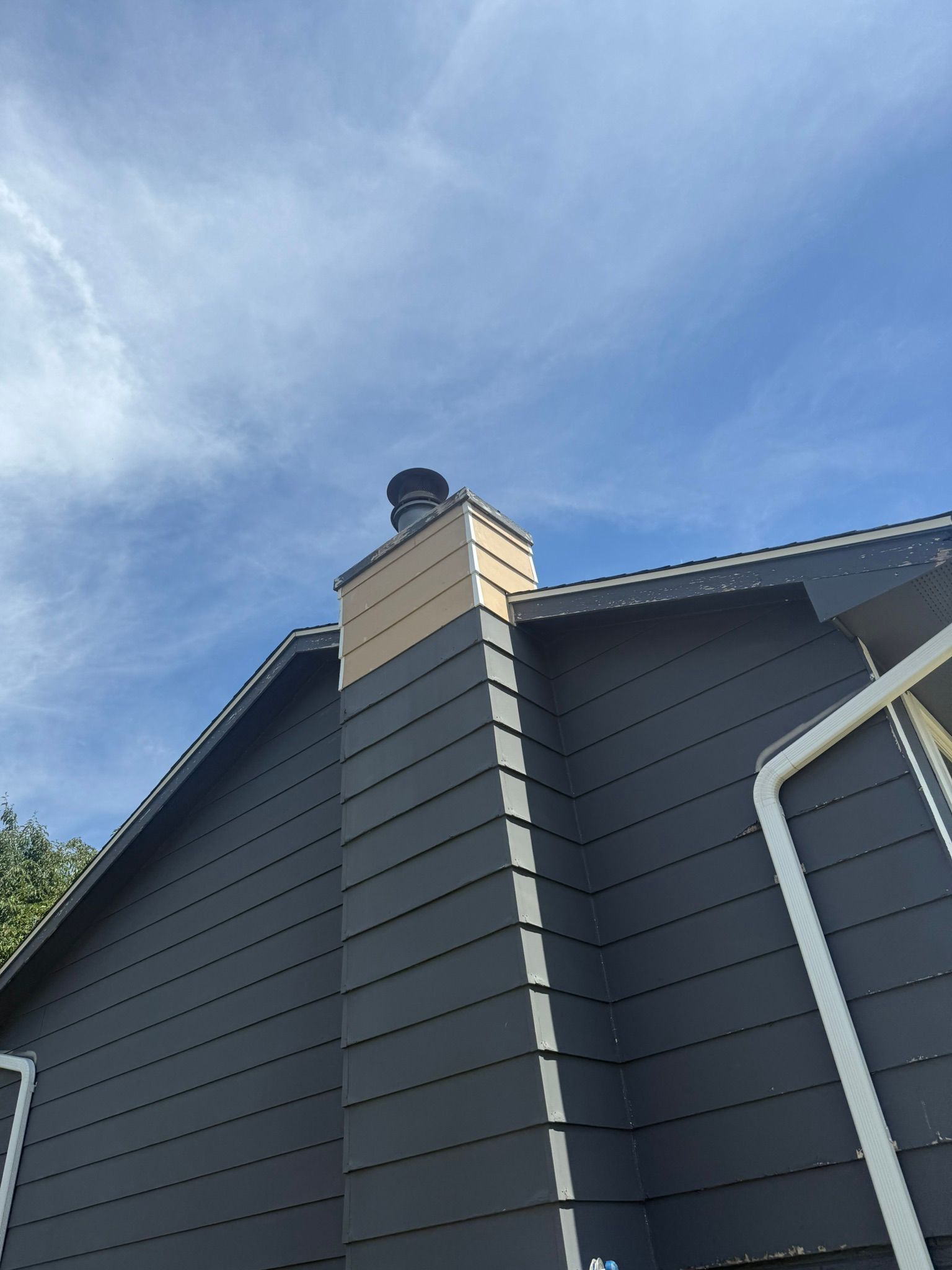 A house with a chimney on the side of it and a blue sky in the background