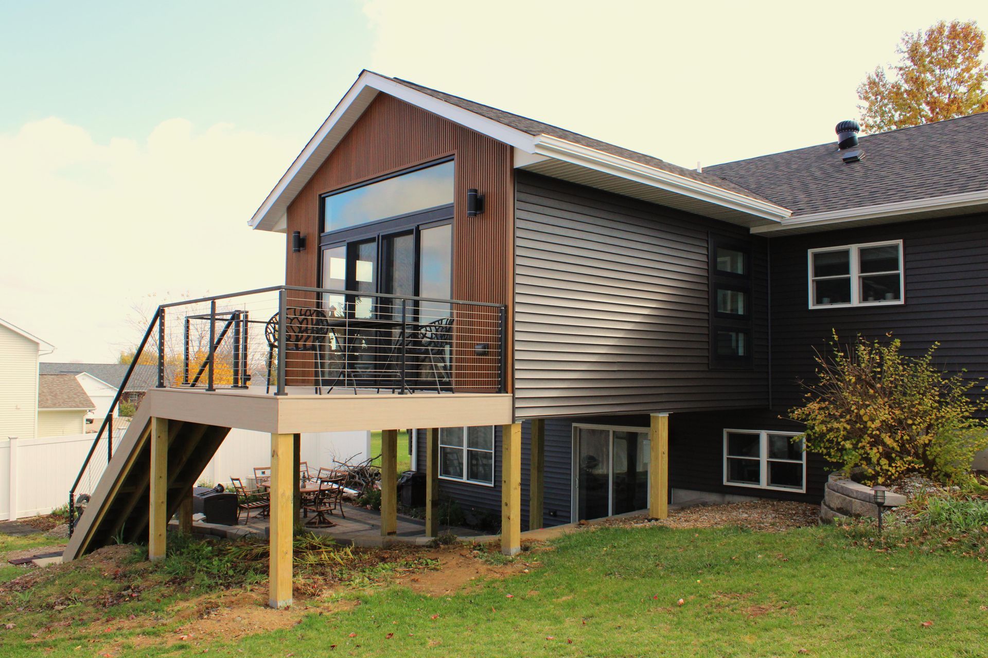 The back of a house with a large deck and stairs leading up to it.