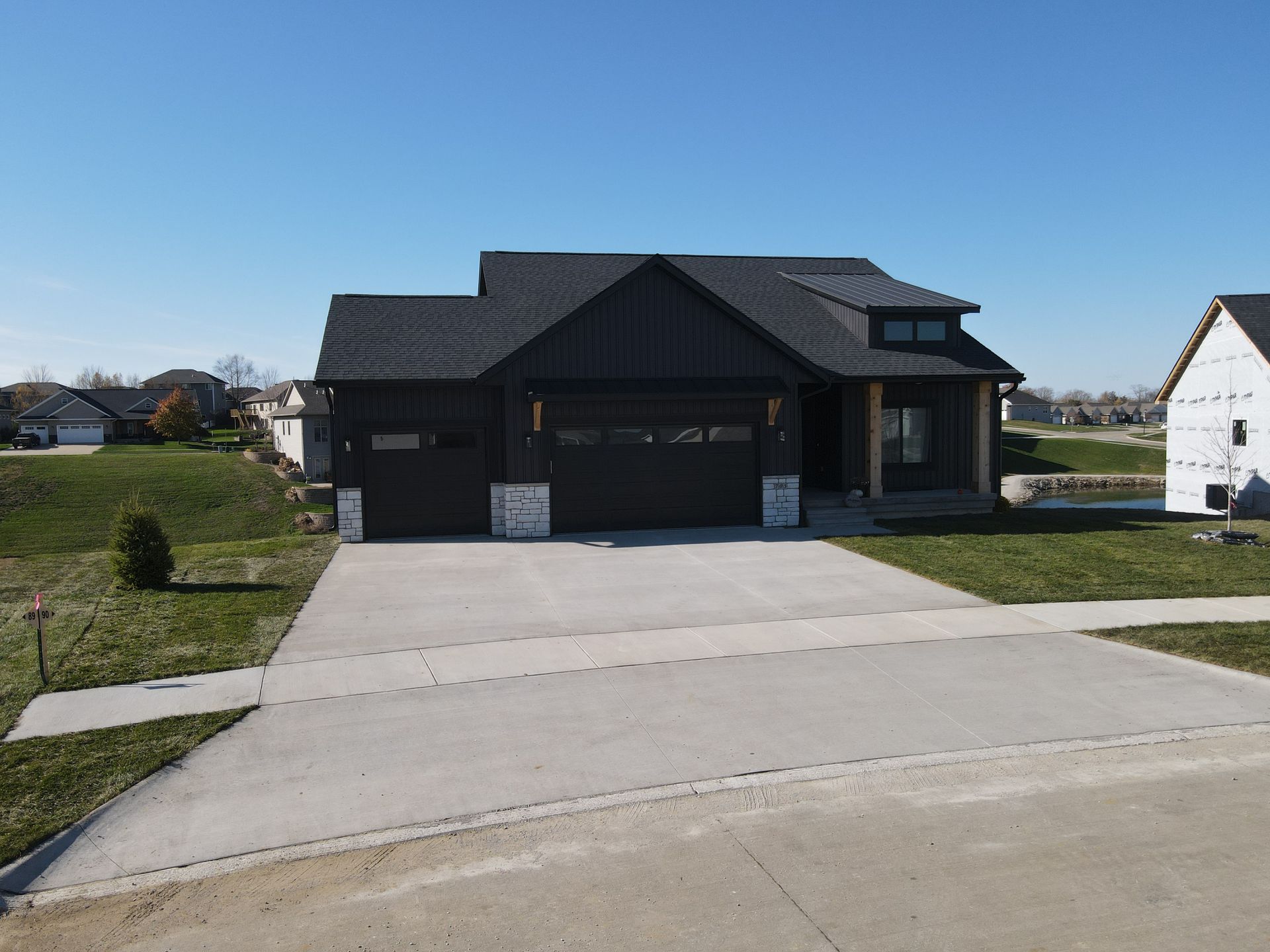 A black house with a concrete driveway in front of it