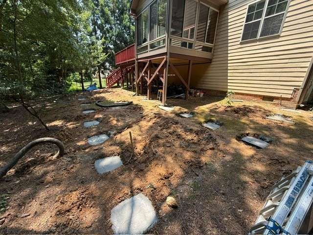Backyard with stepping stones, dirt, and house under construction.