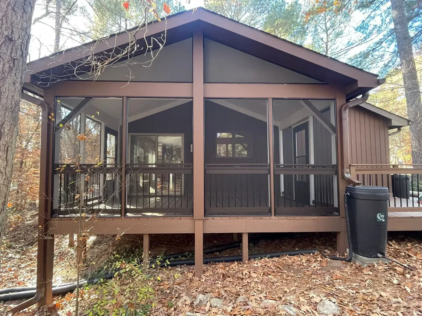 A small house with a screened in porch in the woods.