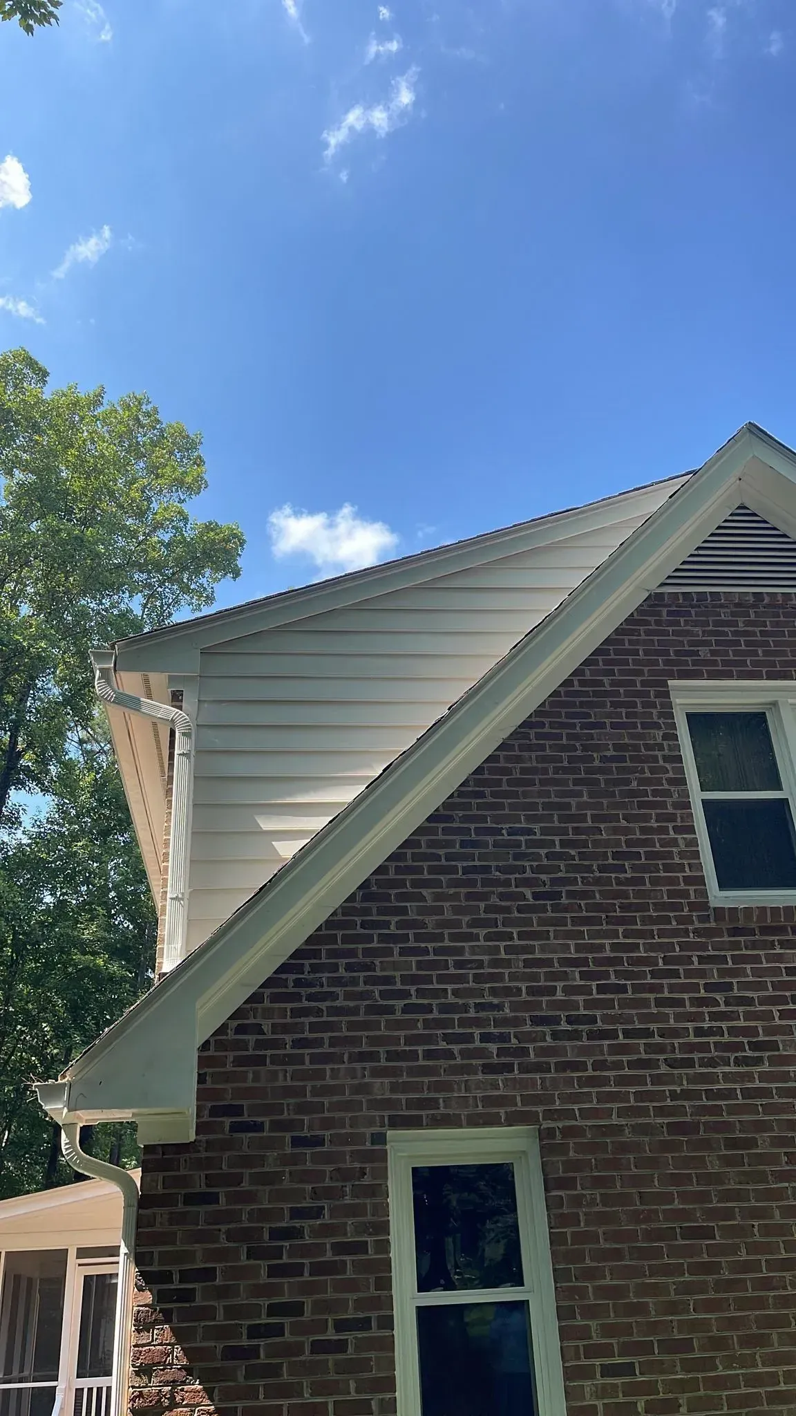 A brick house with a white roof and a blue sky in the background.