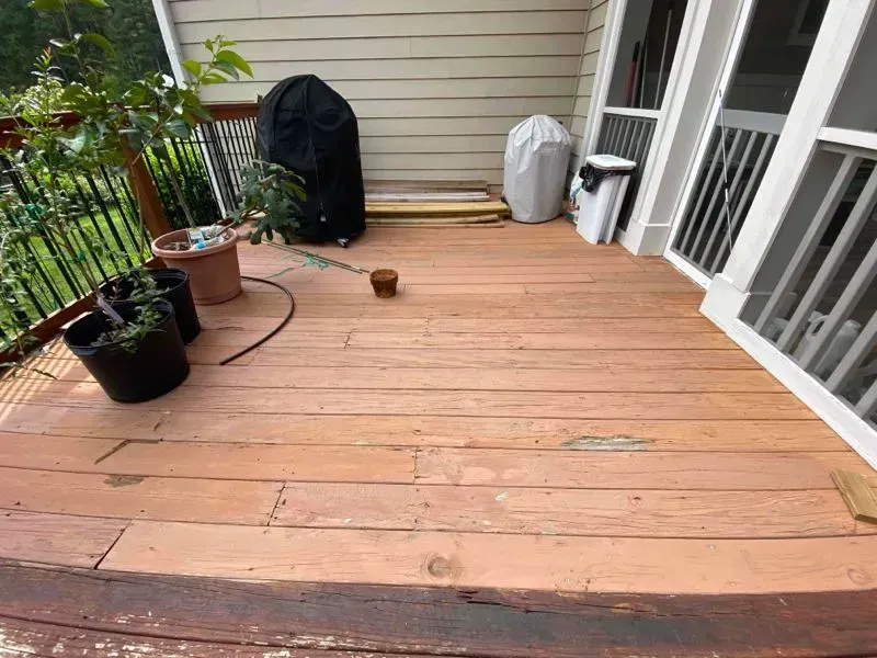 A wooden deck with potted plants and a grill on it.