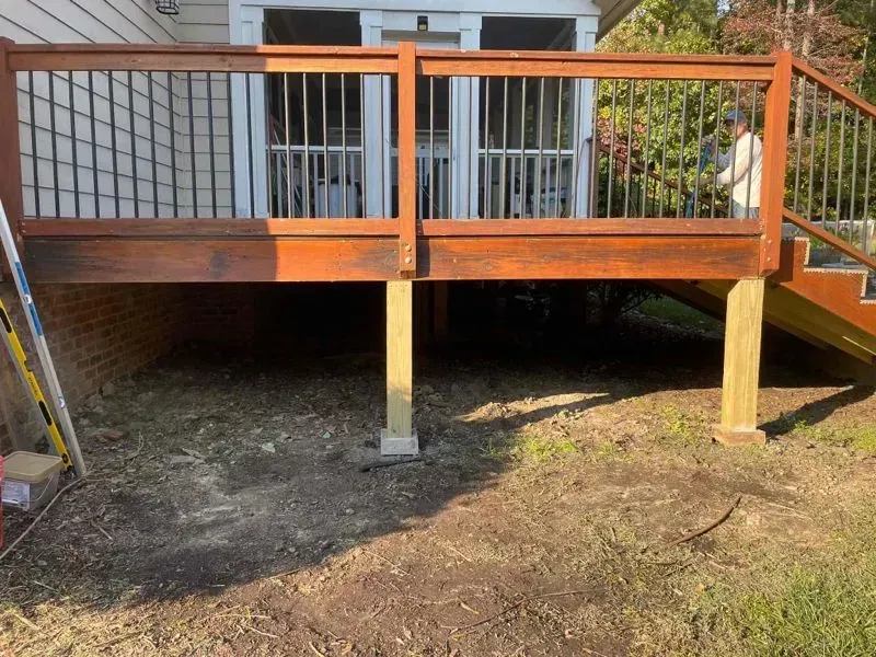 A wooden deck with stairs leading up to it is being built in front of a house.