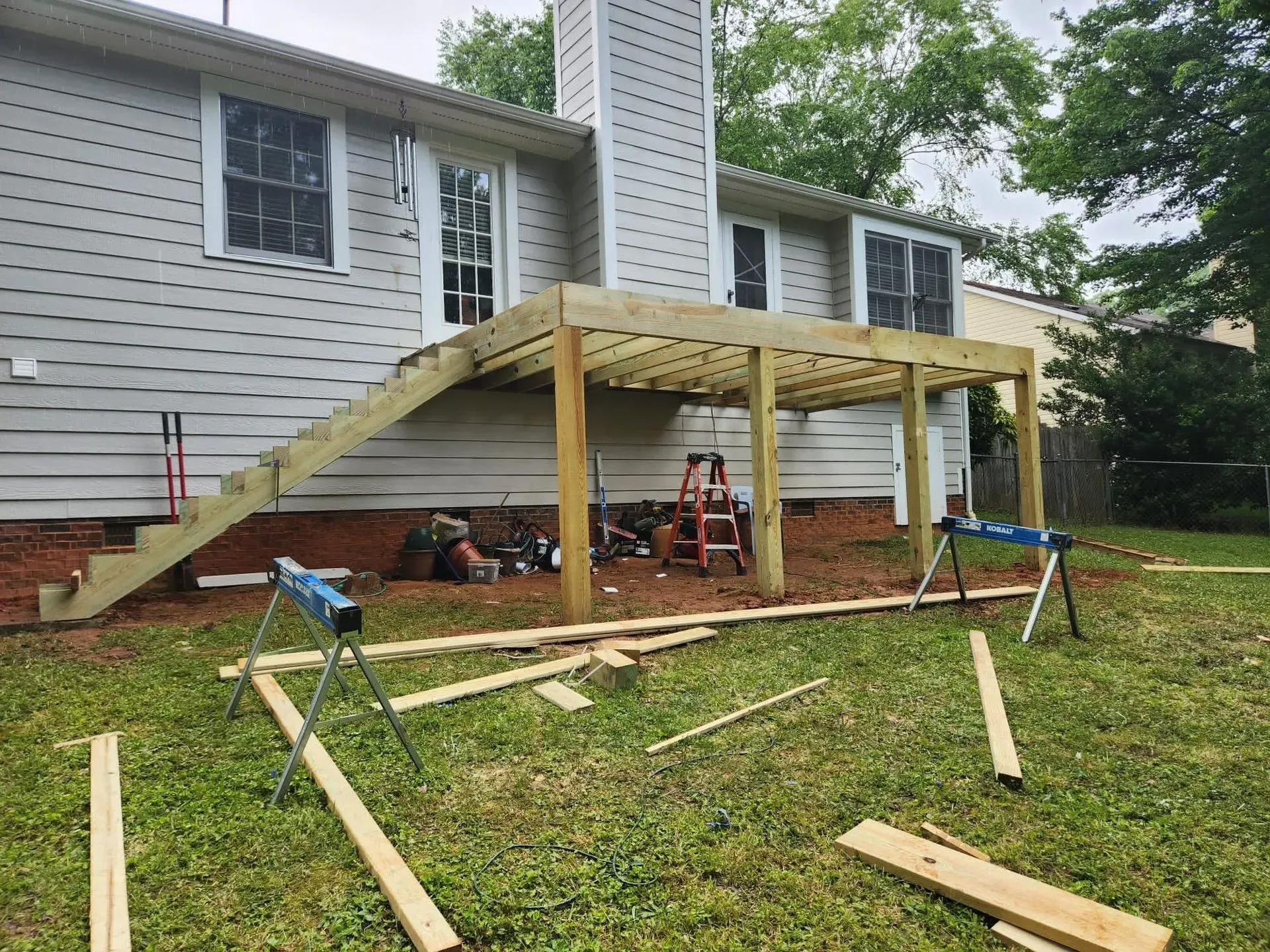 A wooden deck is being built in the backyard of a house.
