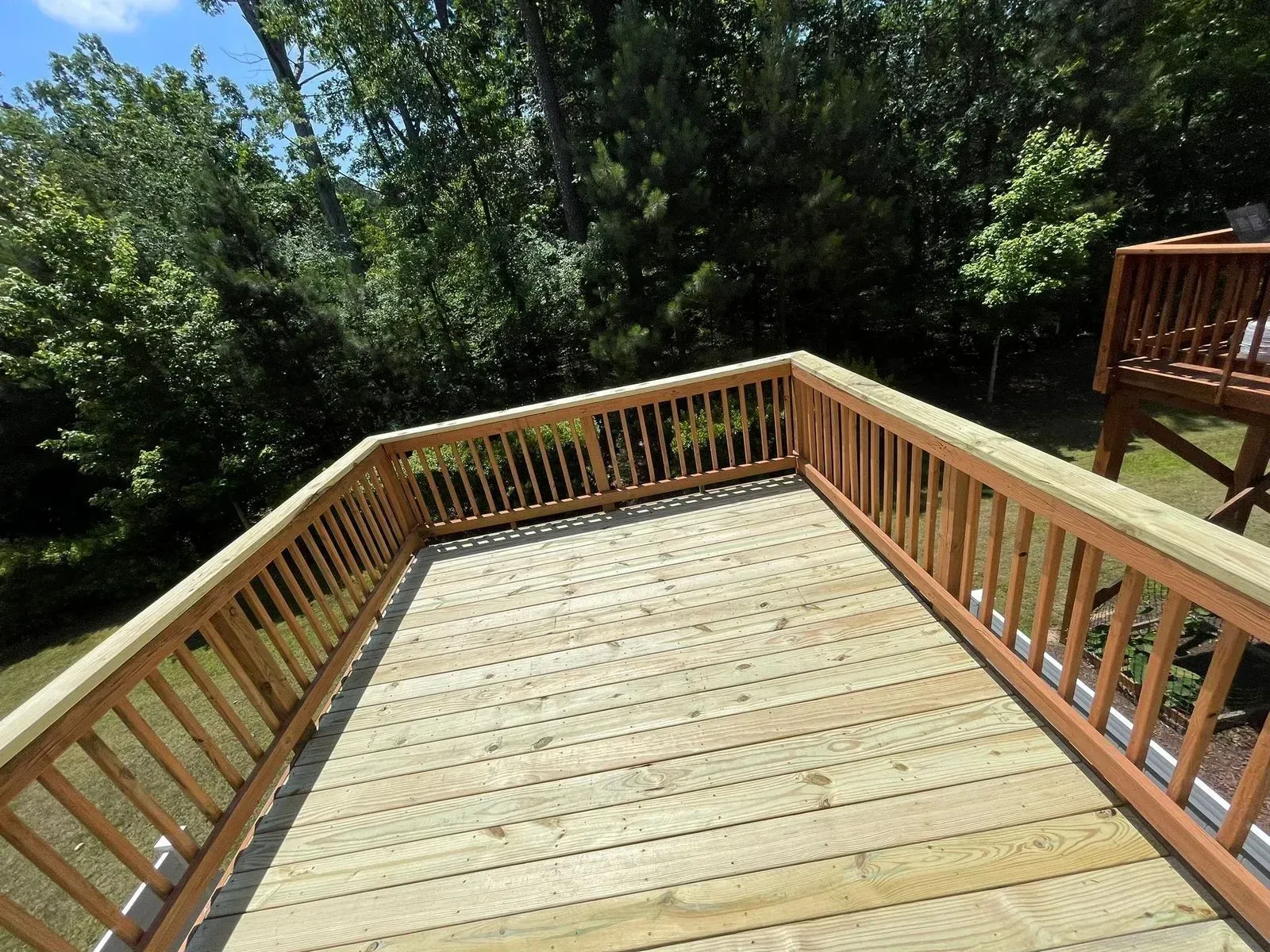 A wooden deck with a railing and trees in the background.