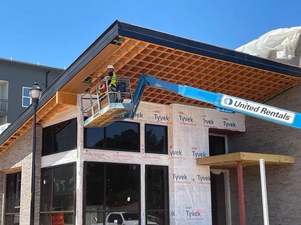 A man on a crane is working on the roof of a building.