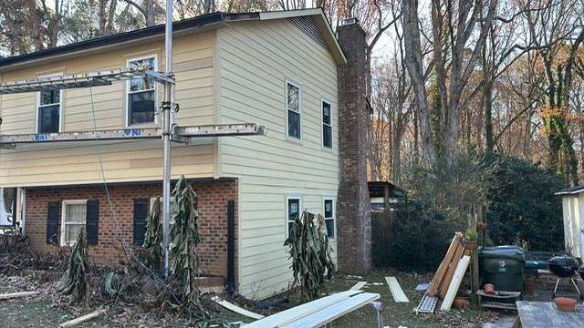 House being renovated with scaffolding and new siding; brick lower level.