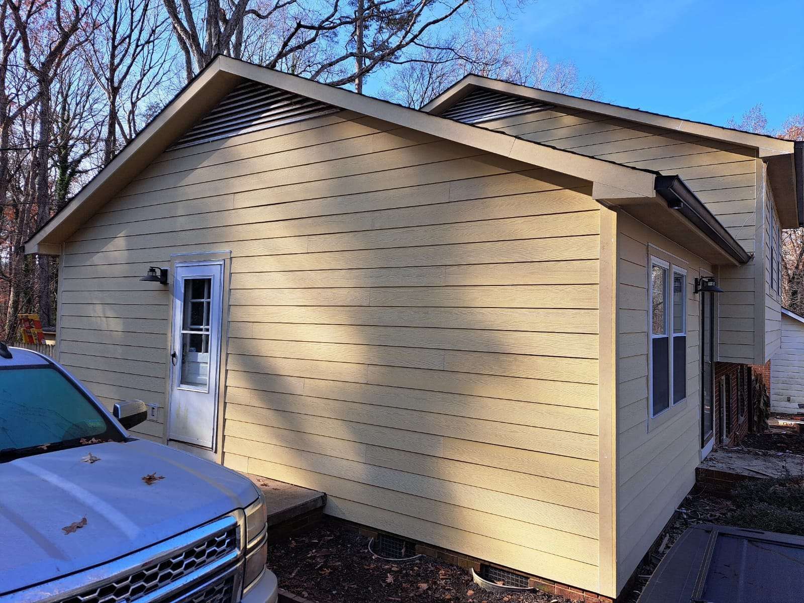 Beige house exterior with a door, windows, and a parked car.