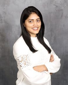 A woman in a white shirt is posing for a picture with her arms crossed.