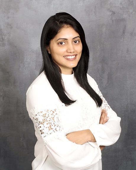 A woman in a white shirt is posing for a picture with her arms crossed.