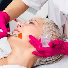 A woman in pink gloves is getting a facial treatment