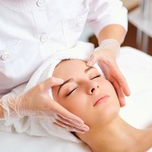 A woman is getting a facial treatment with a towel wrapped around her head.