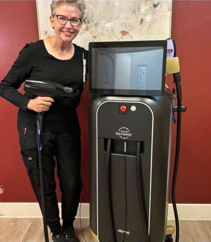 A woman is standing next to a machine holding a hair removal device.