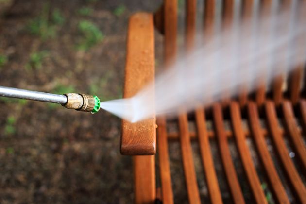 Pressure washer spraying water onto a wooden chair outdoors