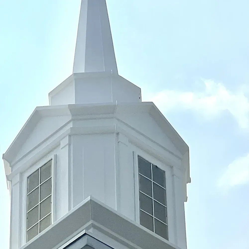 White church steeple with windows against a blue sky