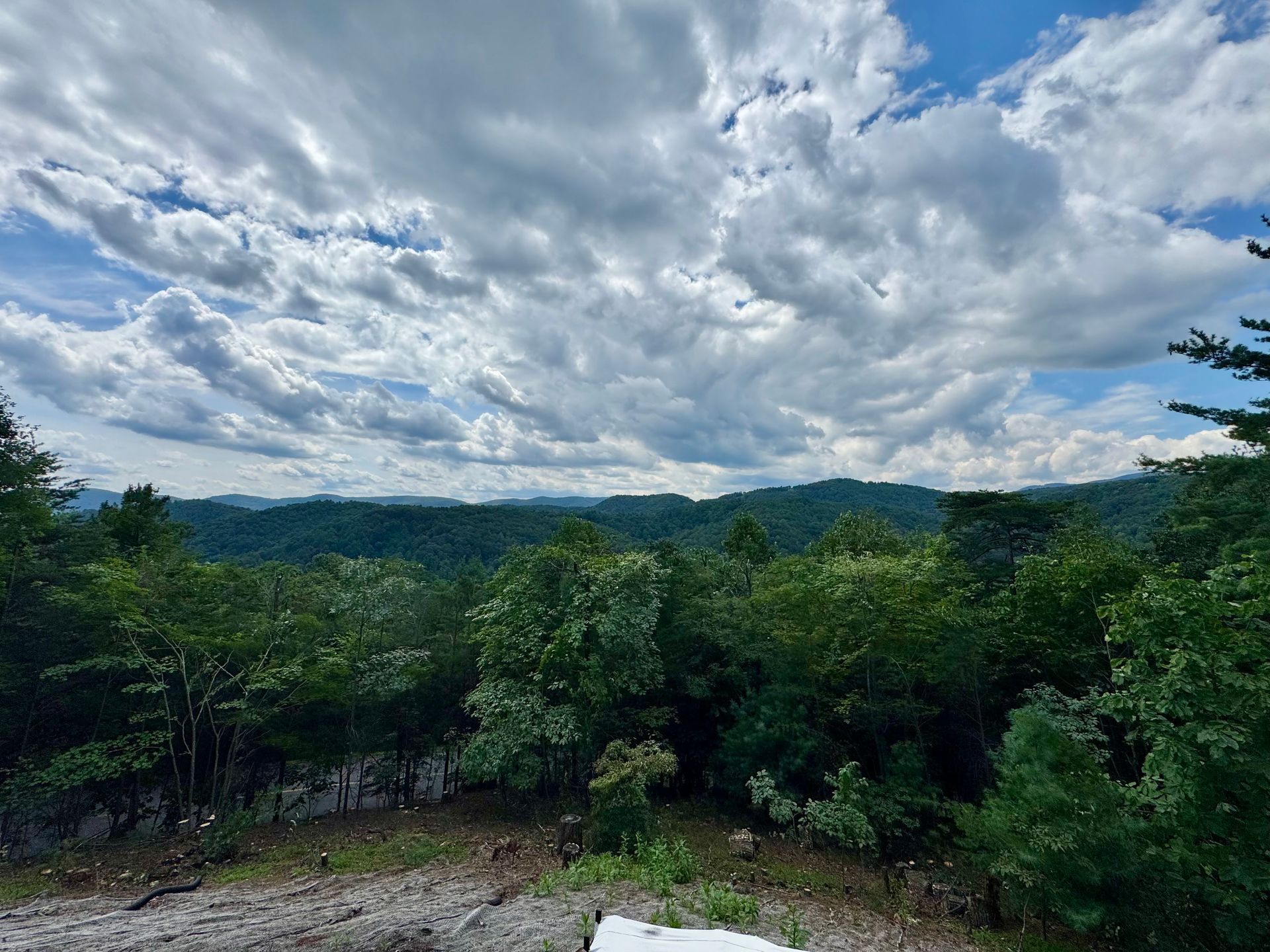 Overlooking lush green hills and trees under a cloudy sky.