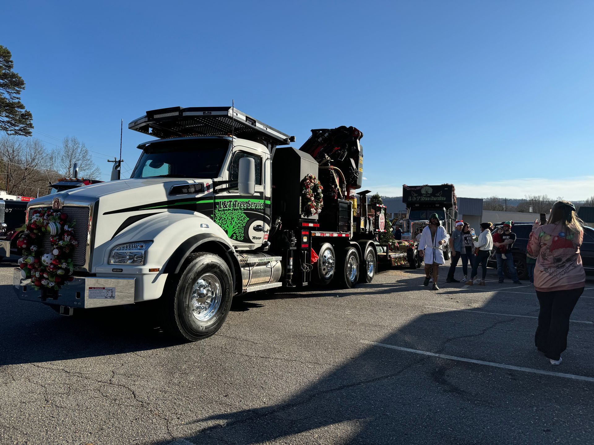 White semi-truck with green logo and Christmas decorations parked outside. People standing nearby.