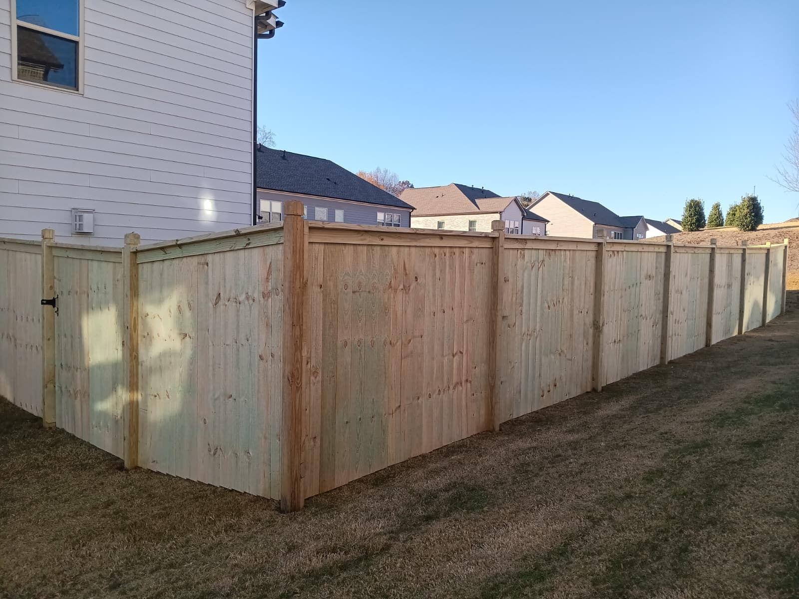 Wooden privacy fence surrounding a grassy backyard.